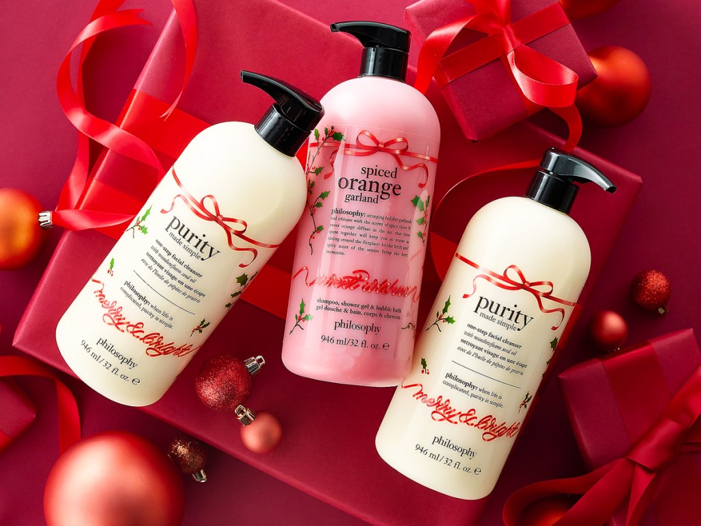 two bottles of Philosophy One-Step Simple Facial Cleanser and one bottle of Spiced Orange Garland Shower Gel surrounded by red ribbons and ornaments