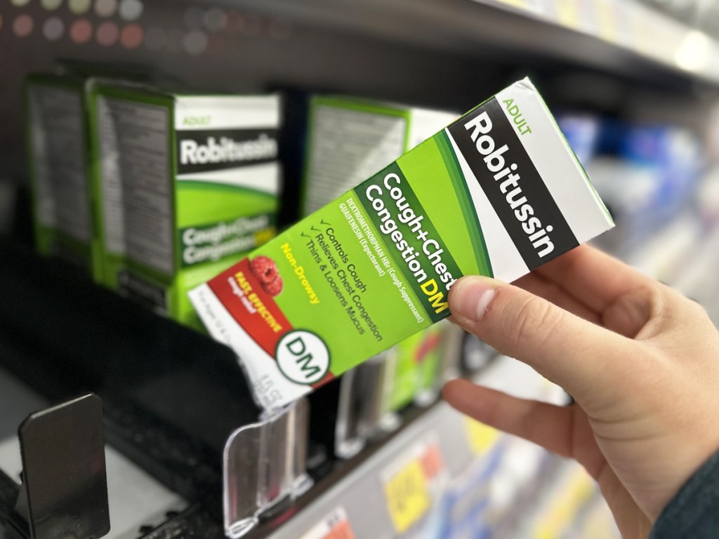 hand grabbing box of Robitussin from store shelf