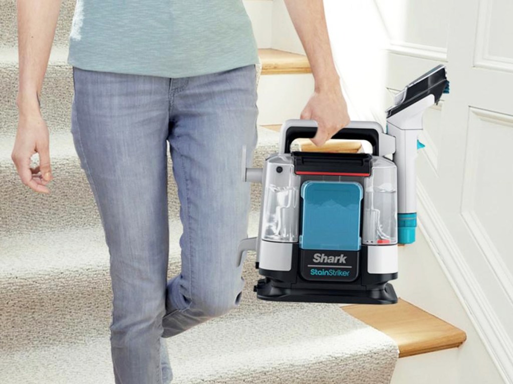 woman carrying Shark StainStriker Portable Carpet & Upholstery Cleaner