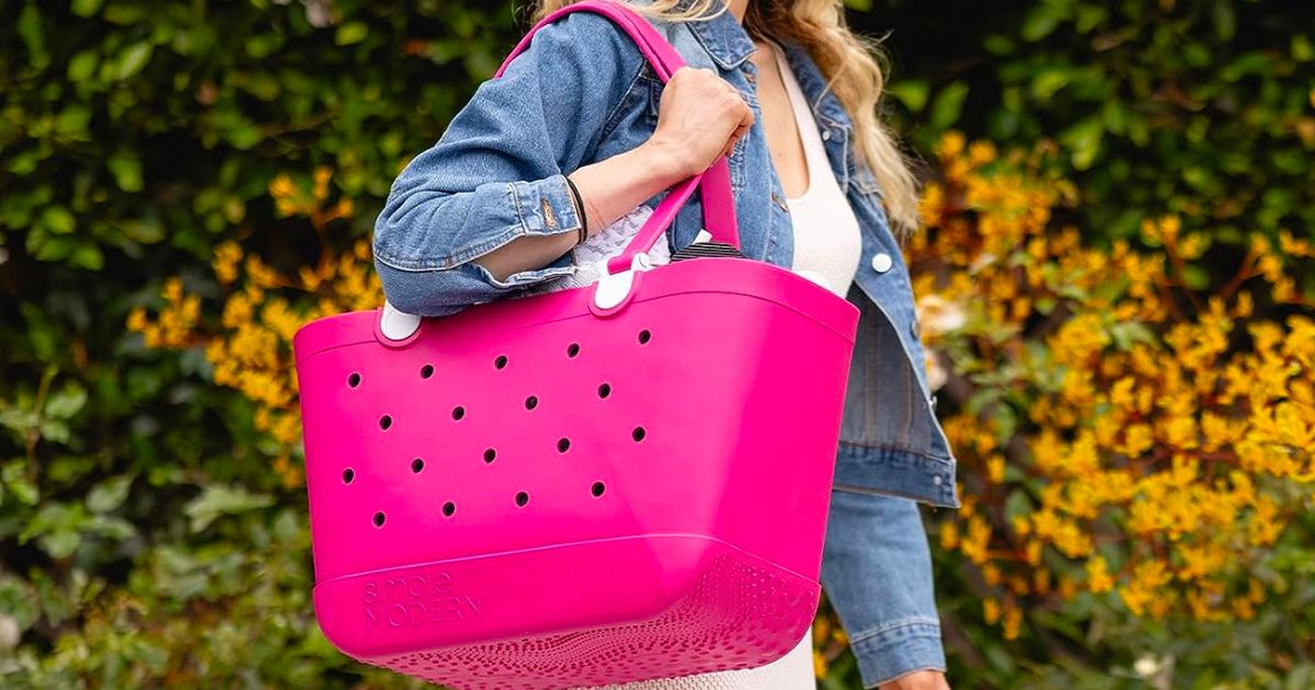 a woman carrying a simple modern getaway tote on her shoulder in malibu pink