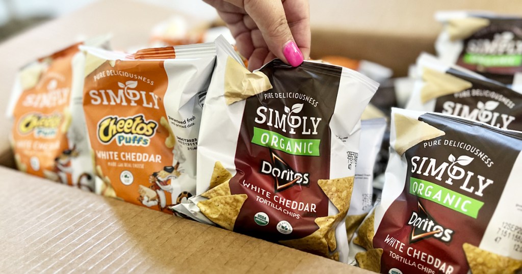 hand grabbing small bags of Simply Doritos & Cheetos from box