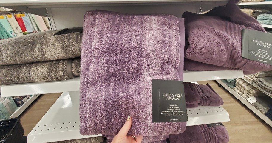 hand grabbing purple bath towel from store shelf