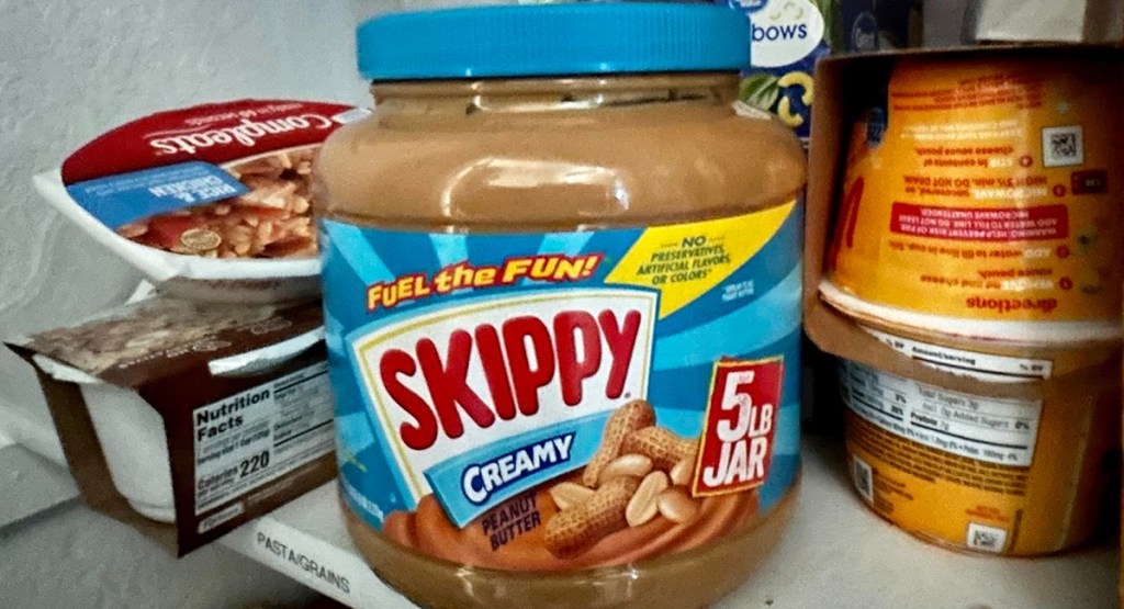 Skippy 5lb jar displayed with other food items in a pantry