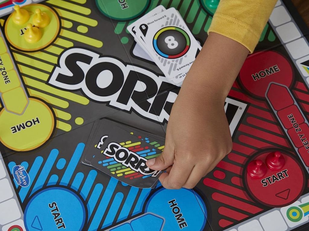 A child's hand playing Sorry! 