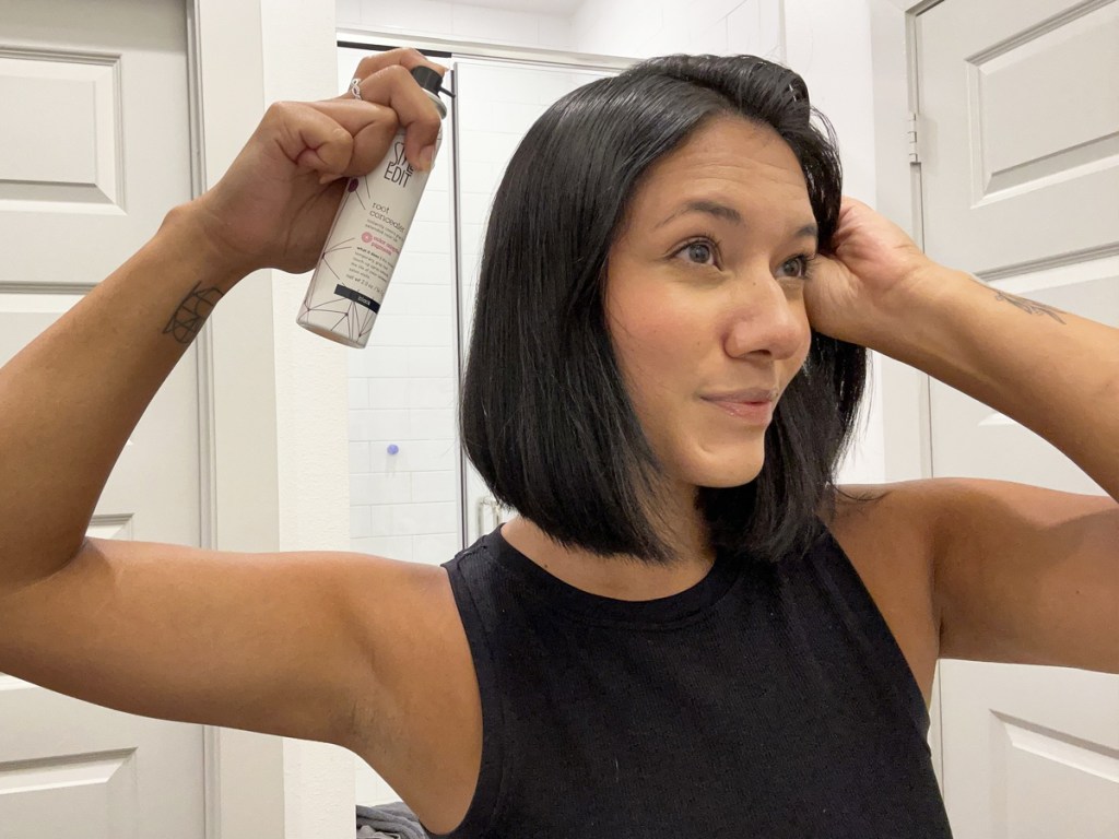 woman spraying root touch-up spray into hair