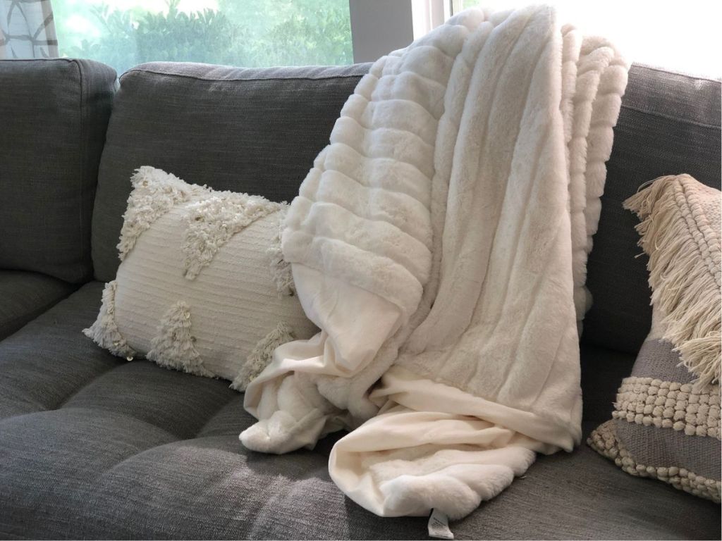 A cozy Throw Blanket thrown over the back of couch