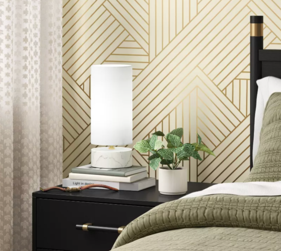 A white Target lamp by threshold on a bedroom nightstand.
