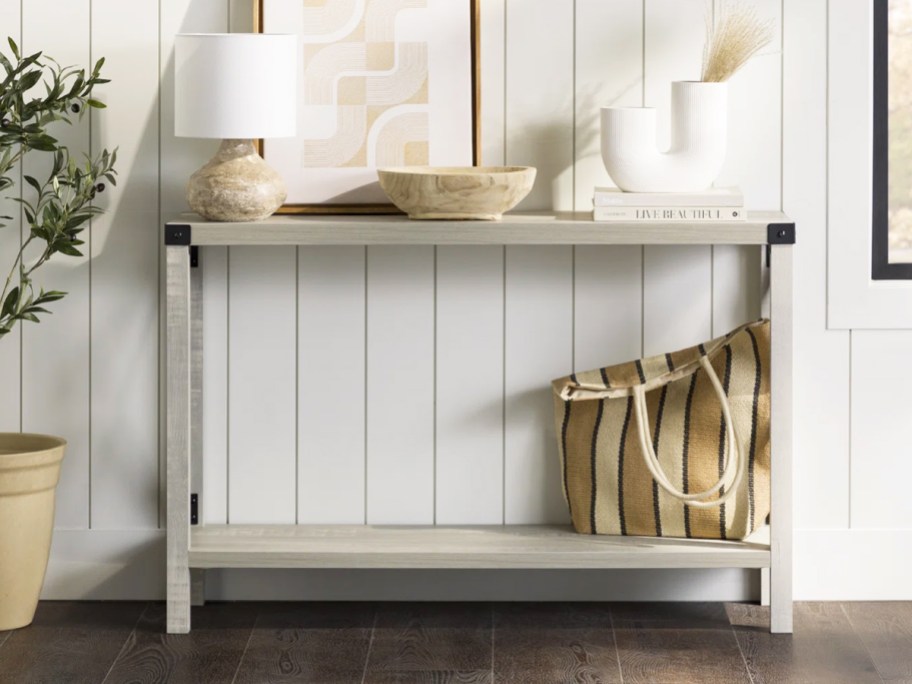 white console table with lamp, bag, and decor on top