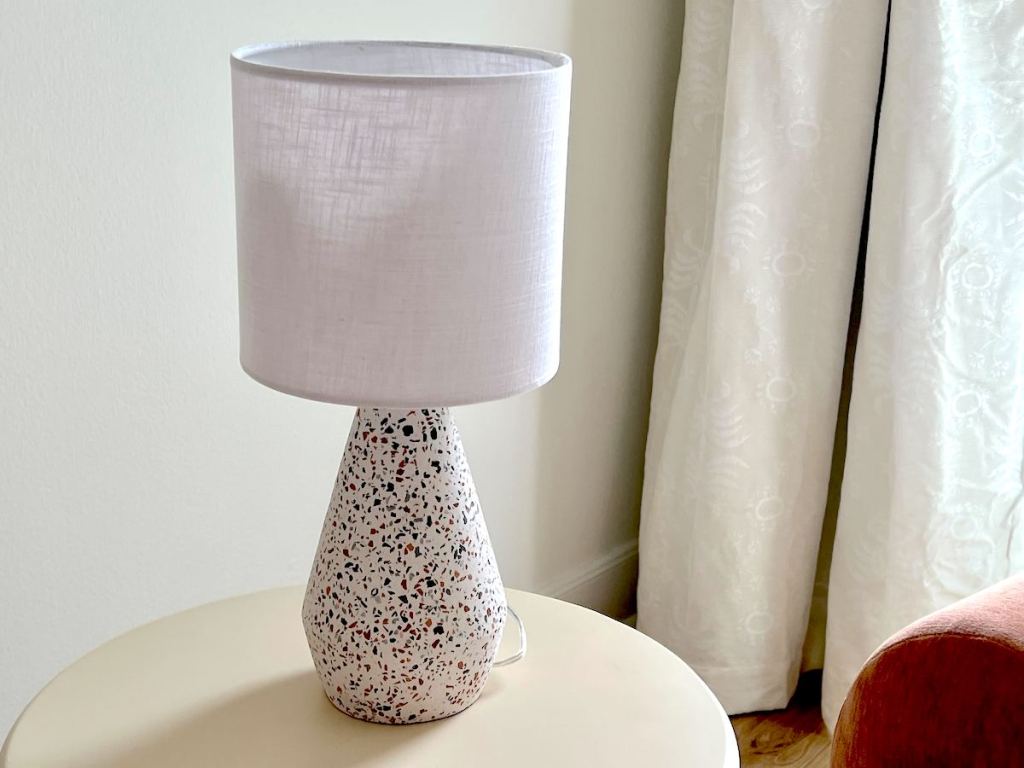speckled lamp with white shade on table