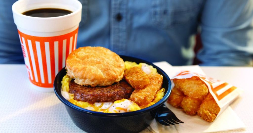 A man sitting at a table with a coffee, hashbrowns, and a Whataburger Breakfast Bowl