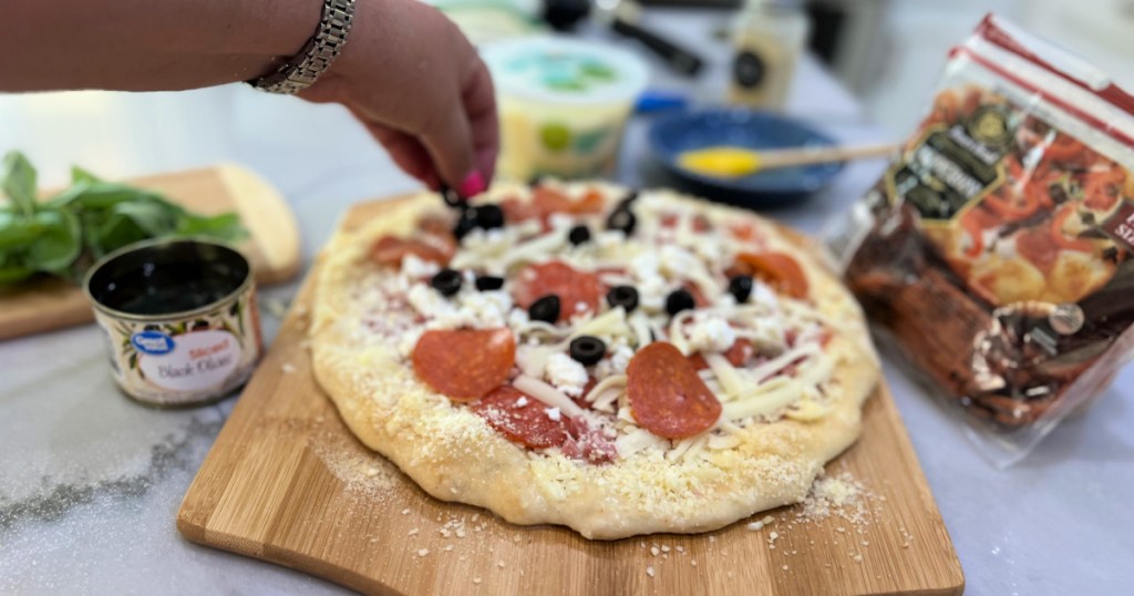 adding black olives and more pepperoni to pizza