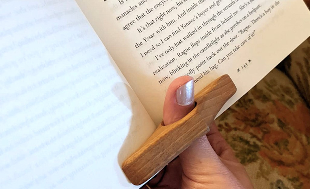 thumb in wooden page holder holding open center of book