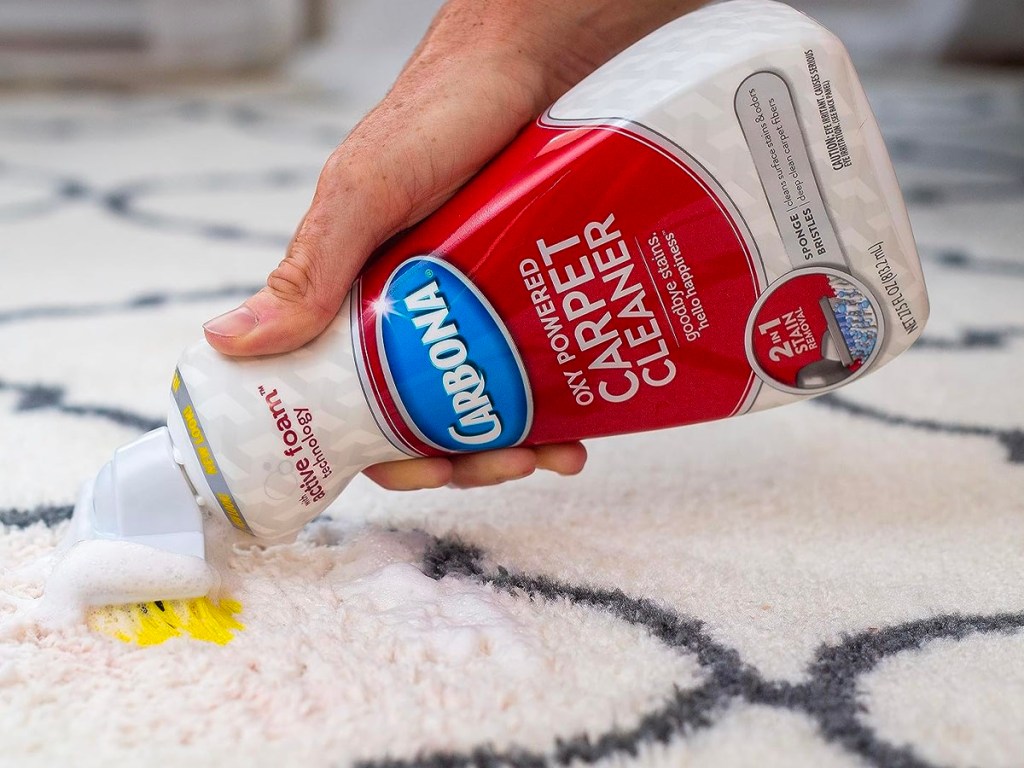 hand using carbona carpet cleaner on rug