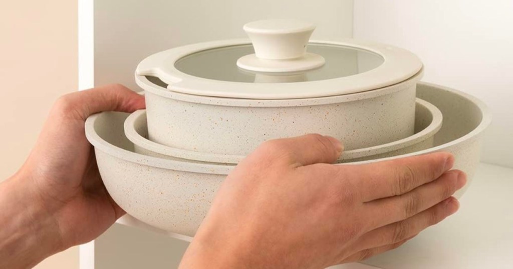 hands putting cookware in cabinet