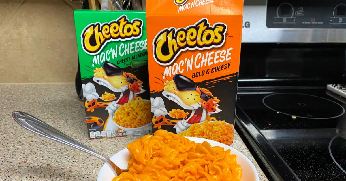 2 boxes of cheetos mac n cheese with a prepared bowl of mac n cheese on a kitchen counter