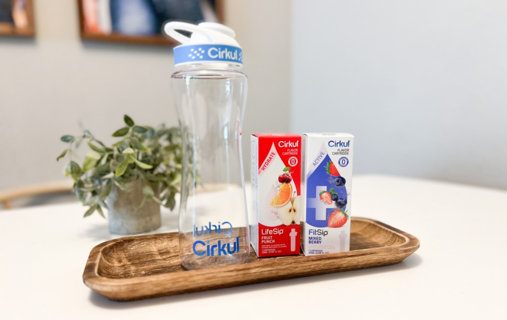 cirkul water bottle and cartridges displayed on a wooden tray on a table
