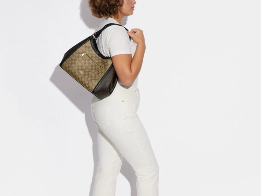 woman wearing white carrying a brown Coach handbag