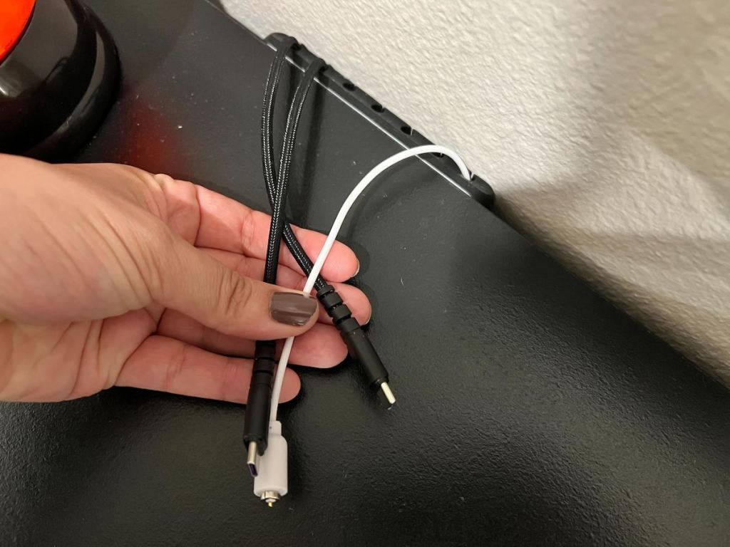 hand holding cords on back of table with cord organizer