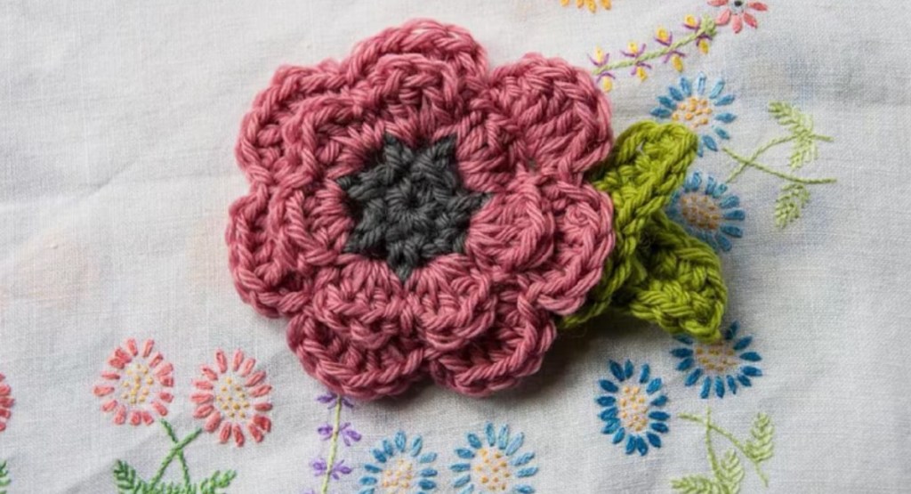 pink crochet flower on embroidered background