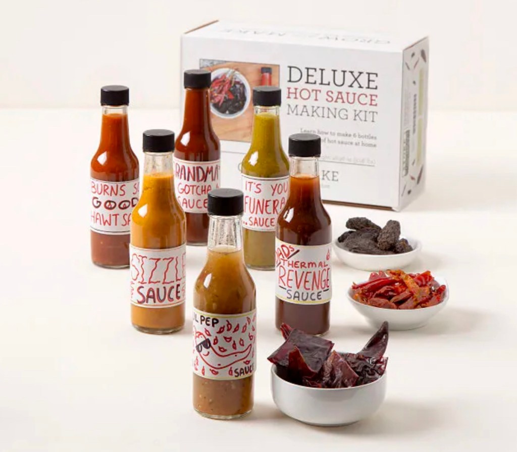 various bottles of hot sauces with deluxe hot sauce making kit on white table