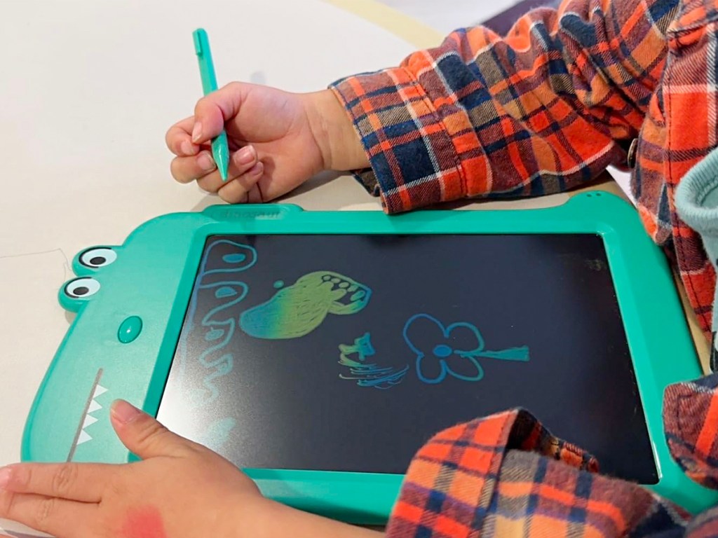 child writing with green dinosaur doodle board 