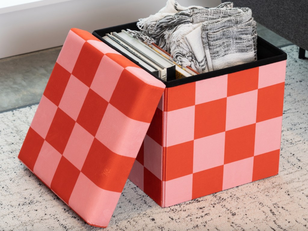 pink and red checkered storage ottoman with blanket inside