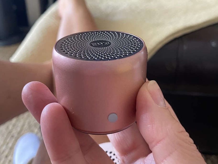 holding a rose gold mini bluetooth speaker