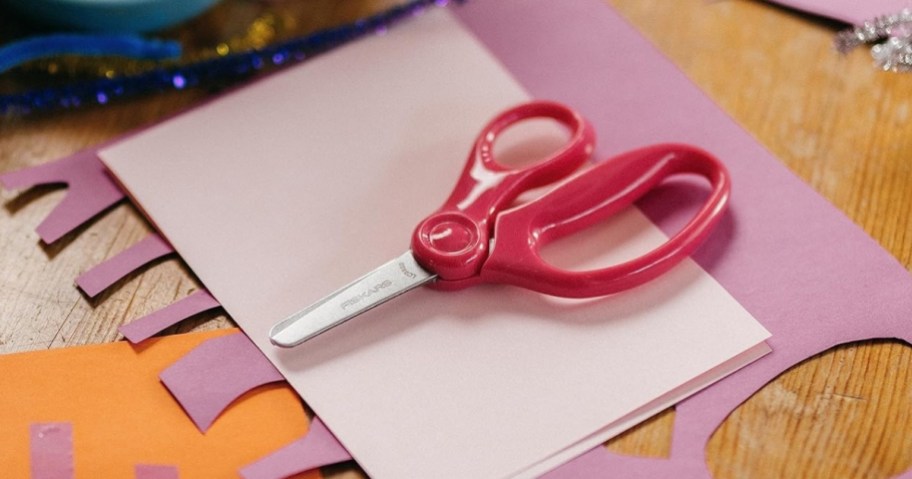 pair of kid's scissors with pink handles on colorful paper