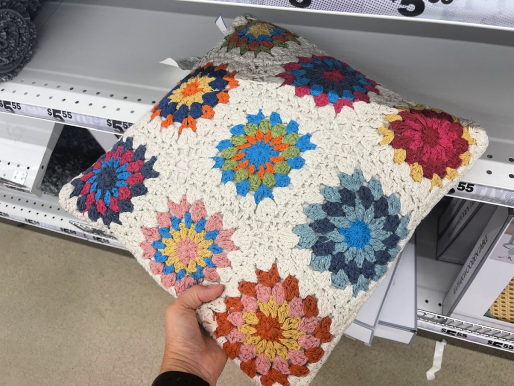 hand pulling a crocheted pillow off a store shelf