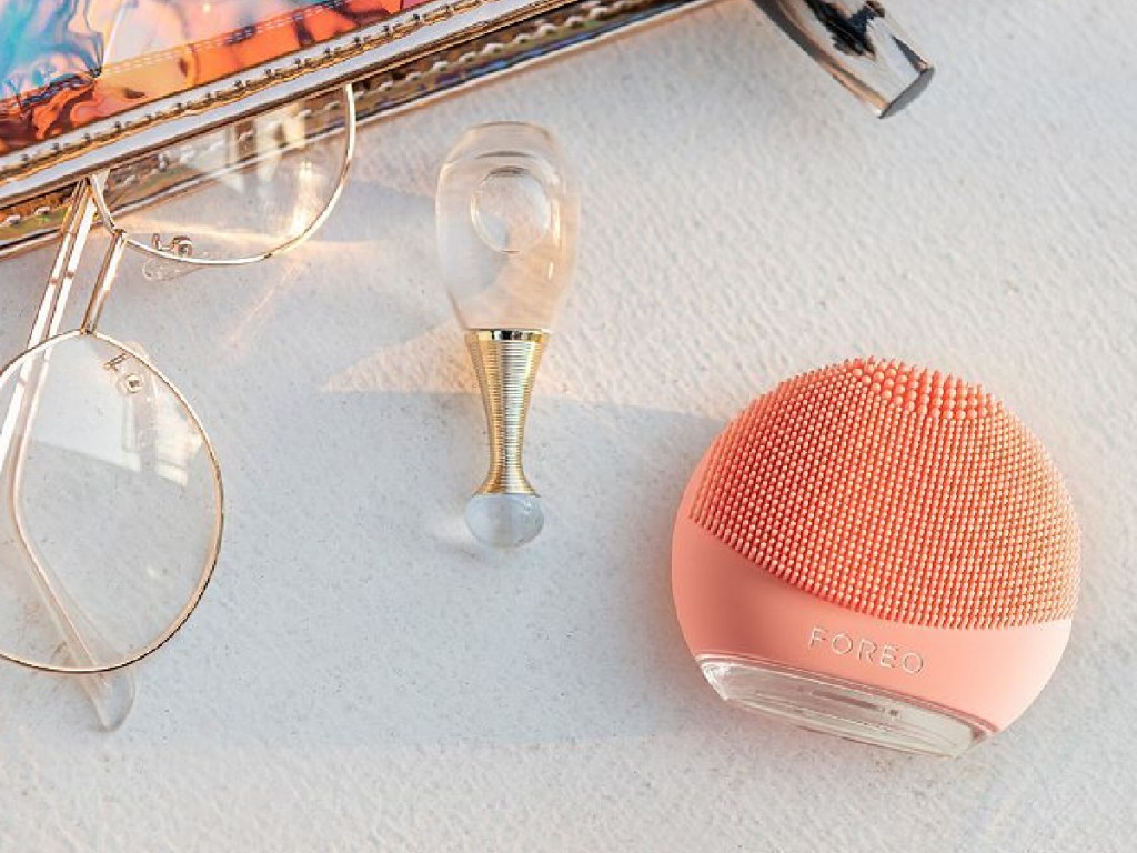 foreo-luna-4-go-facial-system-displayed-next-to-perfume-and-glasses-on-table ULTA أحب حدث بشرتك