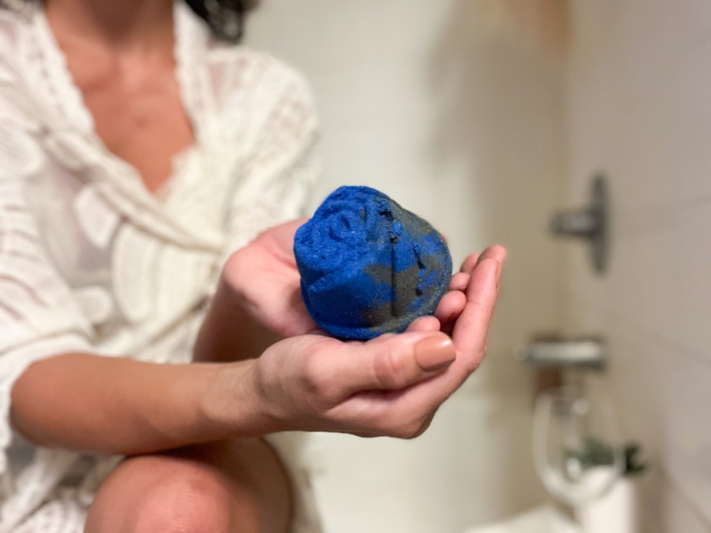 woman holding blue rose shaped bath bomb