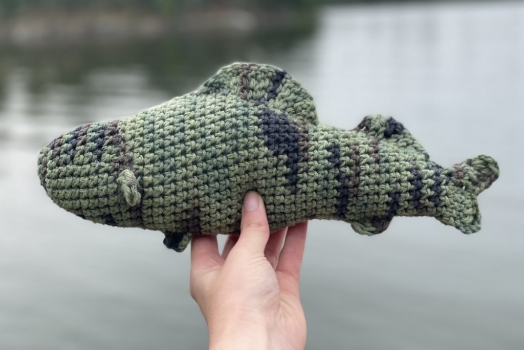hand holding crochet walleye over water