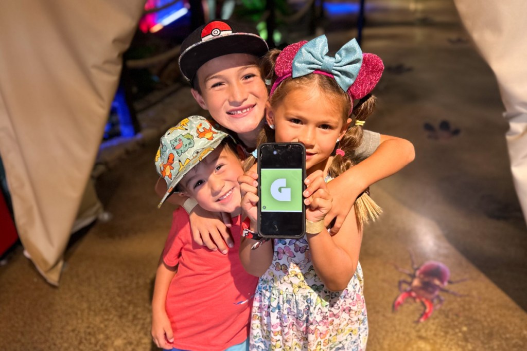 three kids standing together holding phone with get out pass