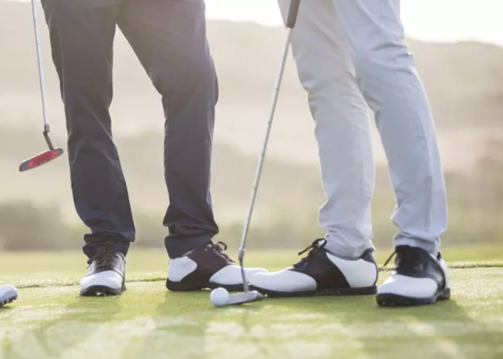 two men standing on golf green with clubs