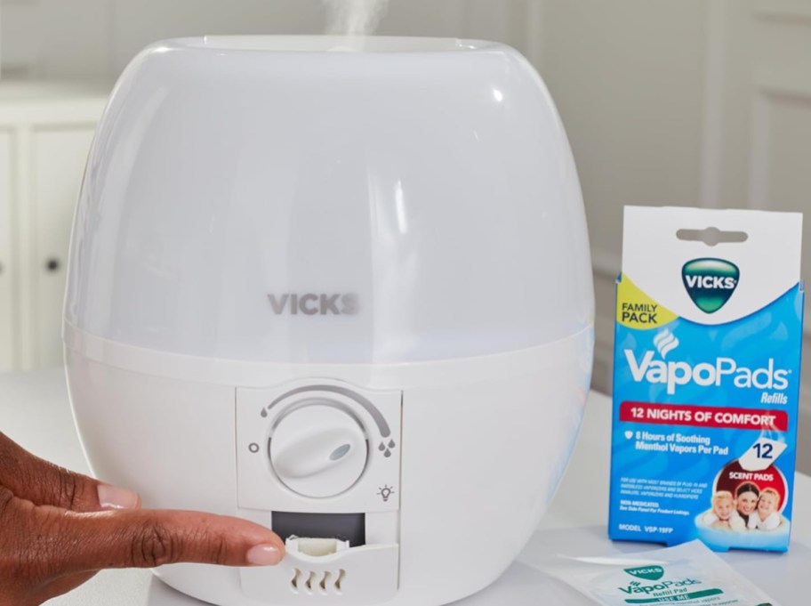 hand closing Vicks humidifier next to Vicks tabs