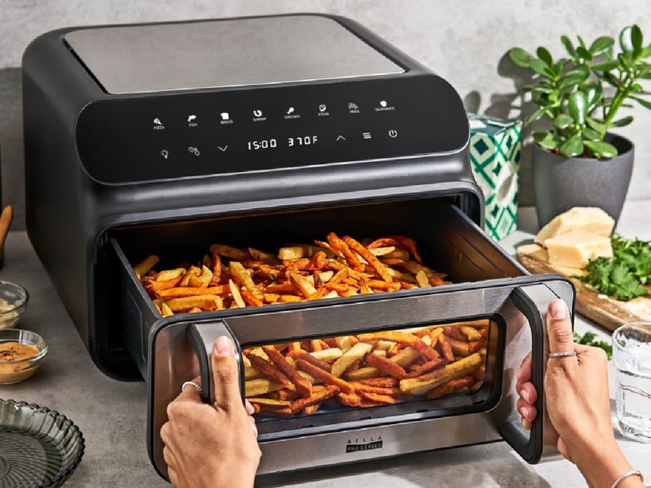 hand pulling Bella Pro Series 10.5qt 5-in-1 Indoor Grill and Air Fryer