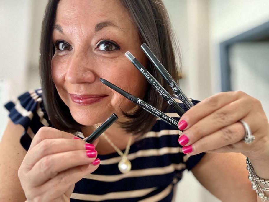 woman holding up sticks of revlon eyeliner