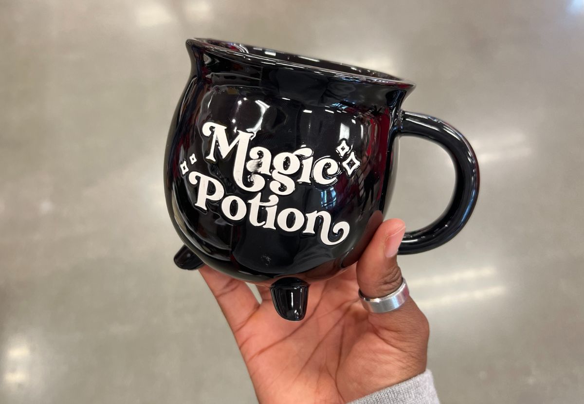 a womans hand holding a magic potion mug