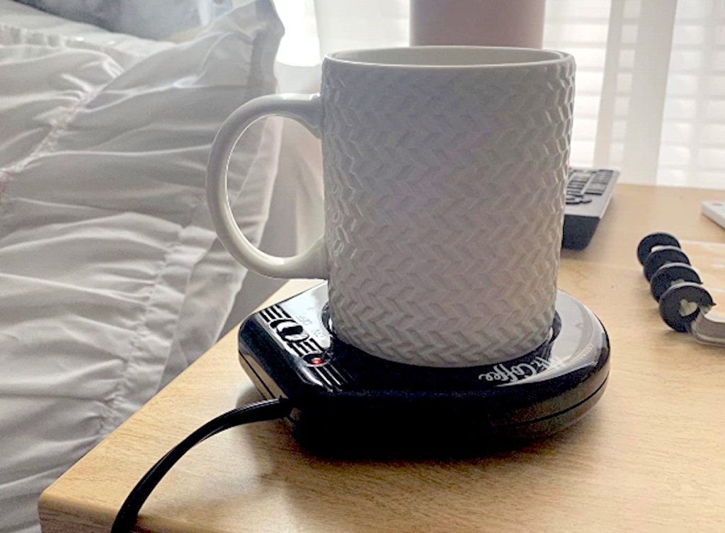 white mug on mr coffee mug warmer on wood nightstand next to bed
