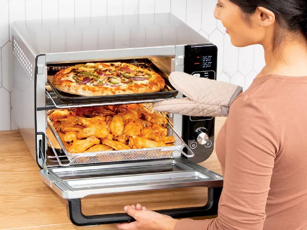 woman pulling a pizza out of a ninja double oven
