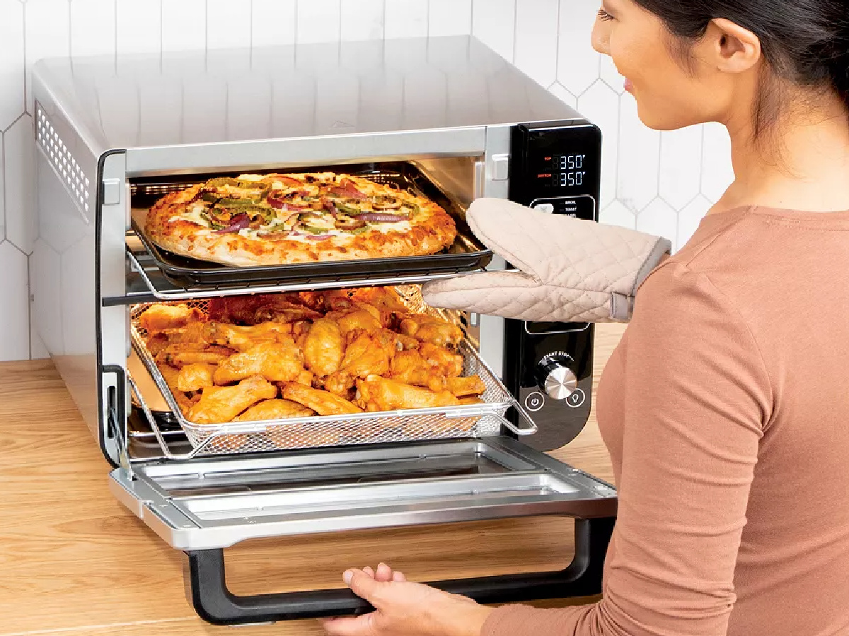 woman pulling a pizza out of a ninja double oven