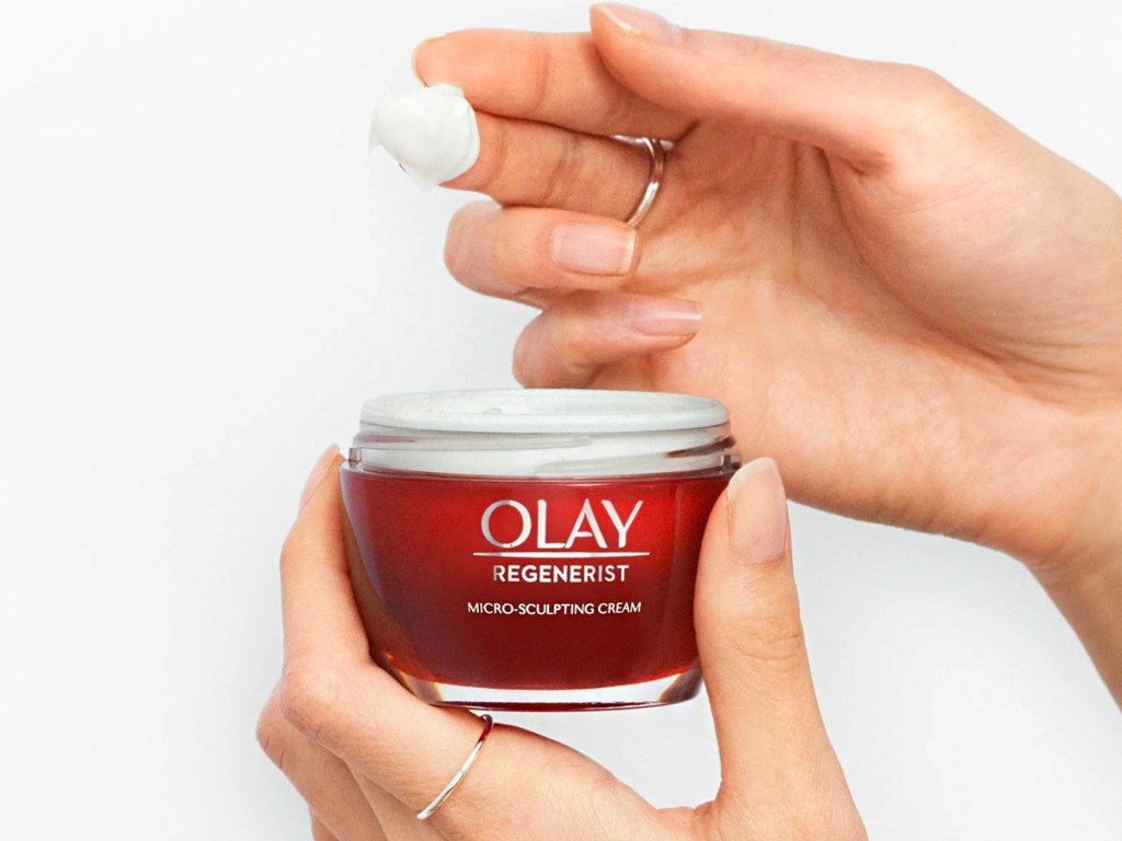 hand taking olay moisturizer out of jar