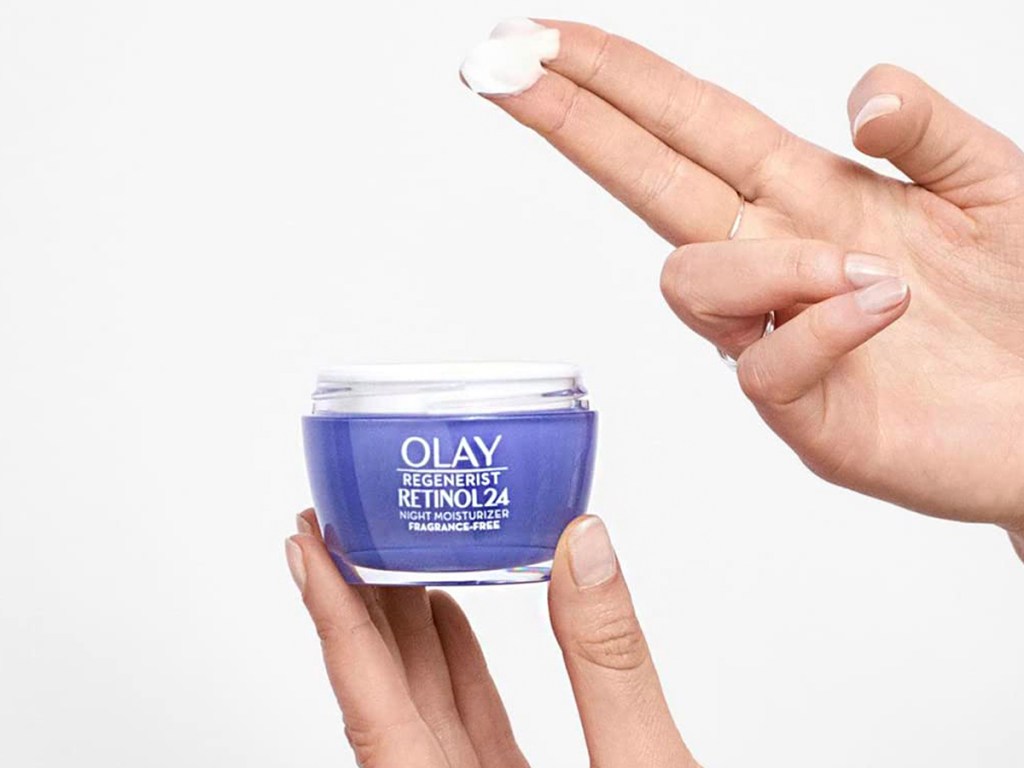 hand taking moisturizer out of olay jar