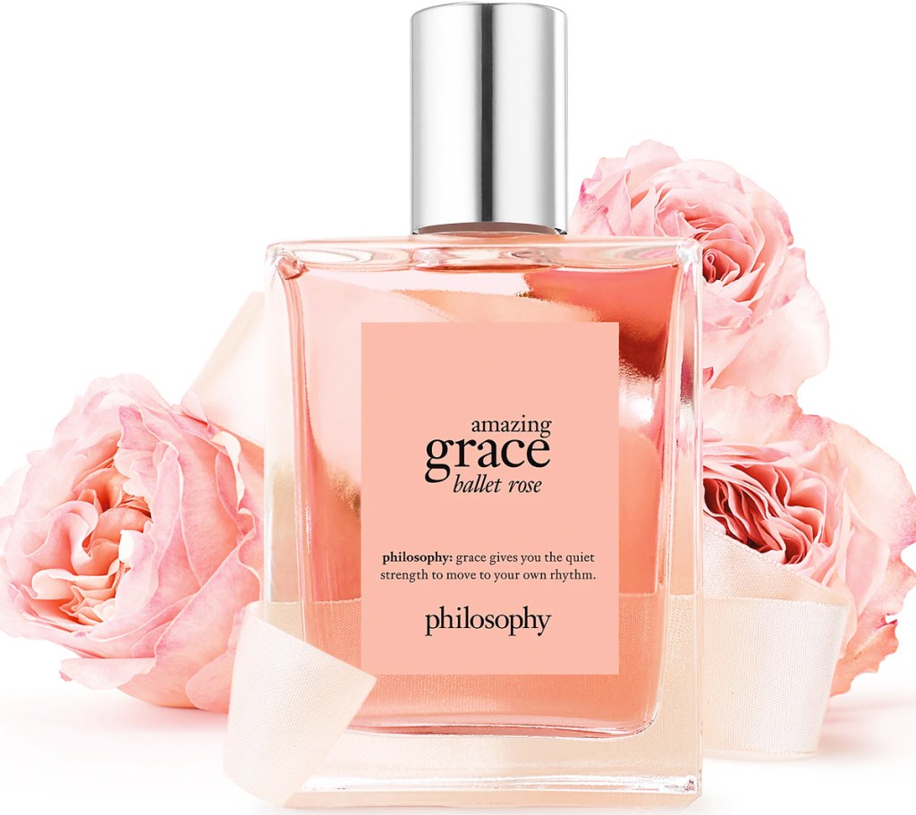 bottle of philosophy Amazing Grace Ballet Rose with roses behind it