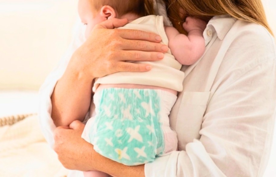 a woman holding a baby wearing a diaper