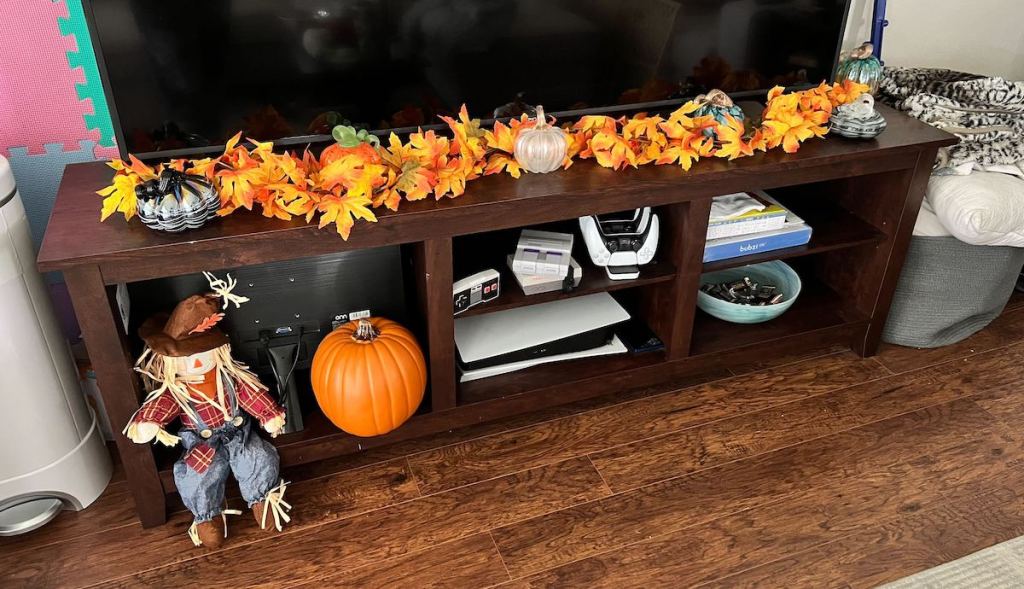 fall decorated wood console table with large TV on top