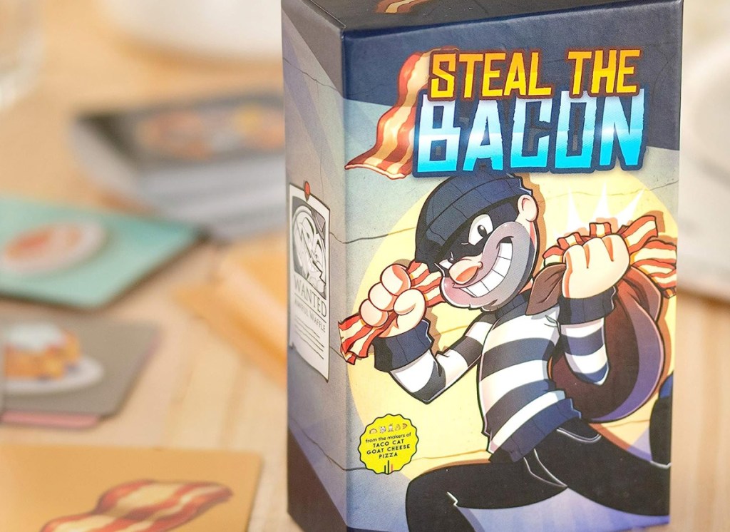 steal the bacon card game displayed in the background of its box