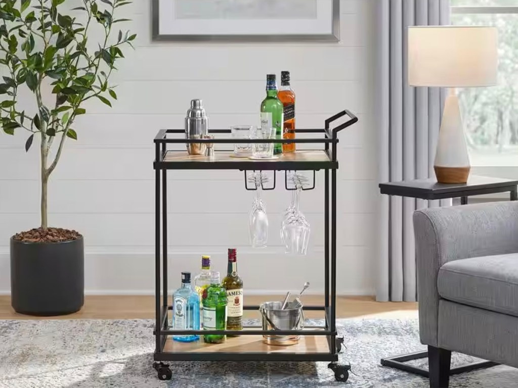 bar cart with alcohol and cups on it