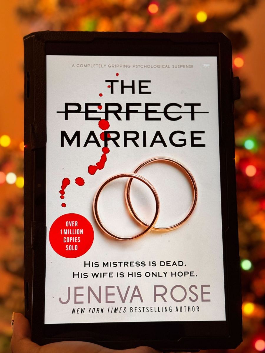 hand holding a tablet with the perfect marriage book in front of christmas tree