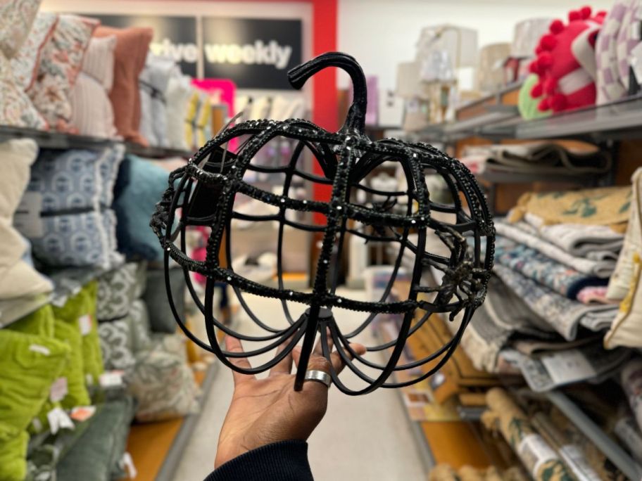 black wire studded pumpkin being held by hand in store